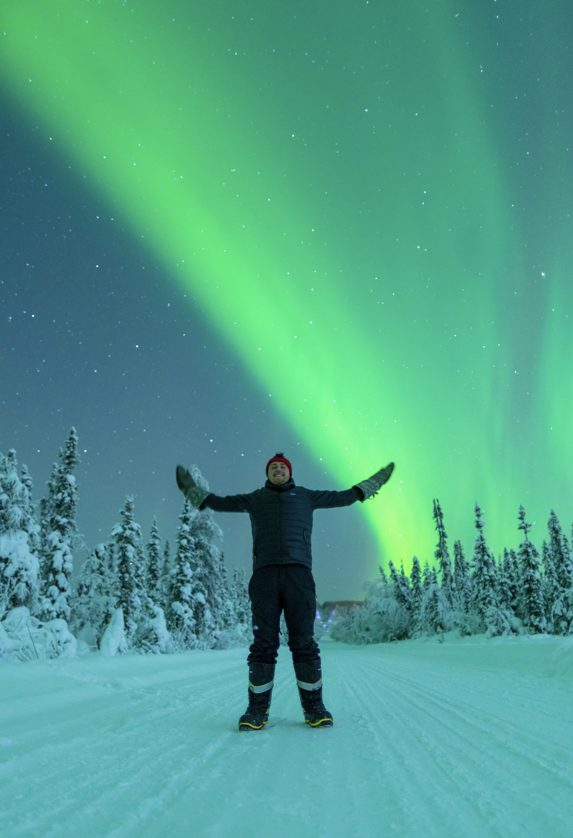 Photograph of Vincent Ledvina standing in snowy landscape with aurora in background